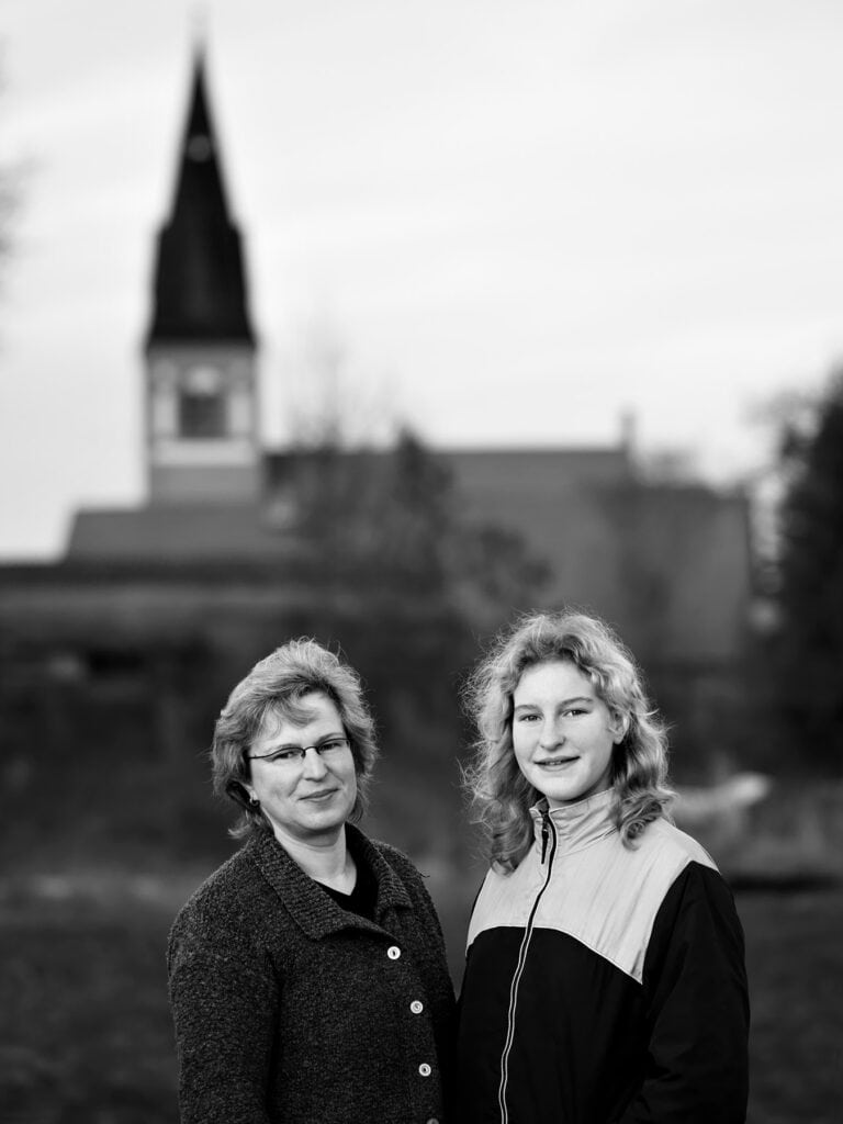 Mutter und Tochter vor der Dorfkulisse aus dem Fotoprojekt Ein Dorf in unserer Zeit von Fotograf Uwe Nölke – dokumentarische Schwarz-Weiß-Fotografie über ländliches Leben und Generationen
